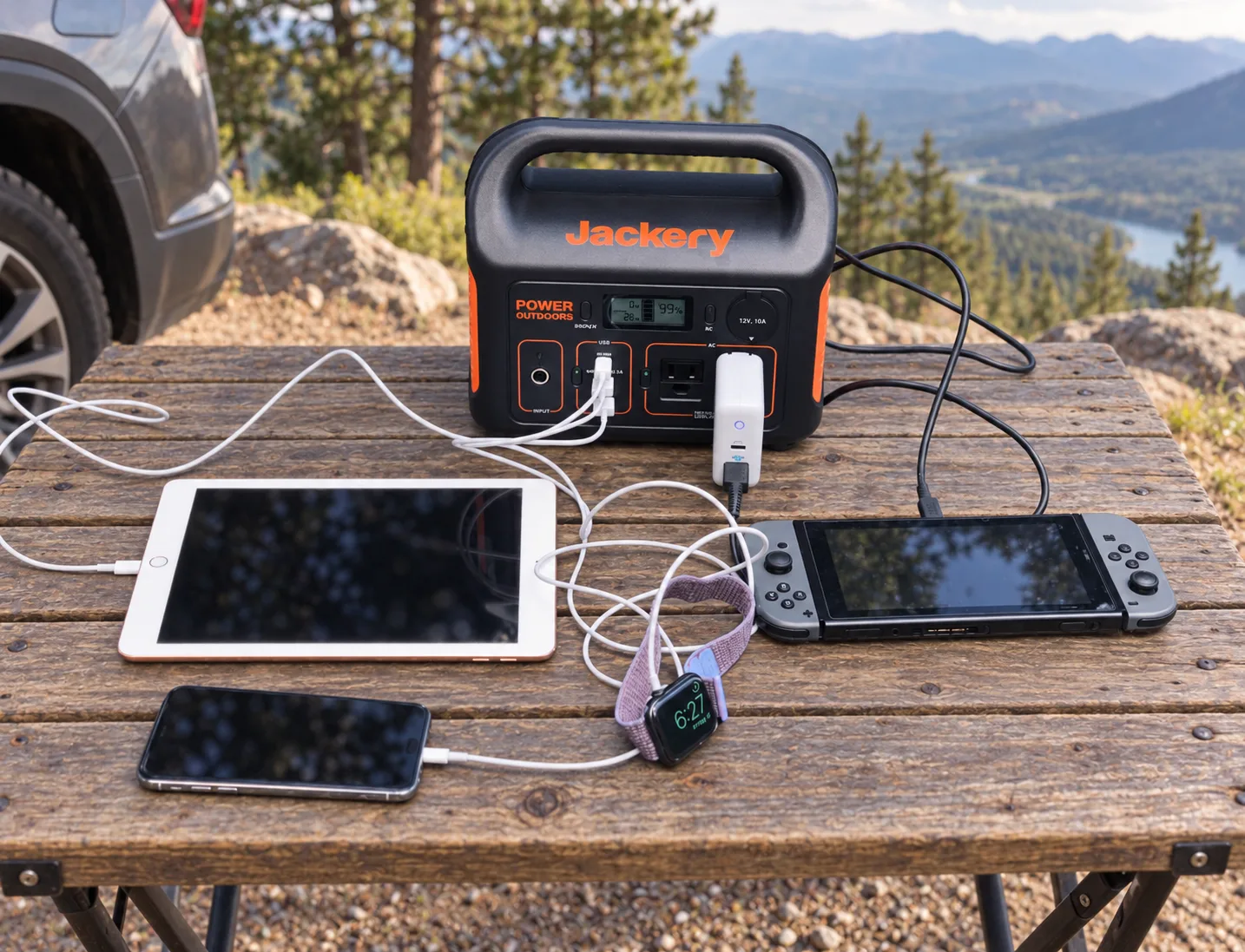 Jackery Explorer 300 charging a tablet, phone, smartwatch, and handheld game console outdoors