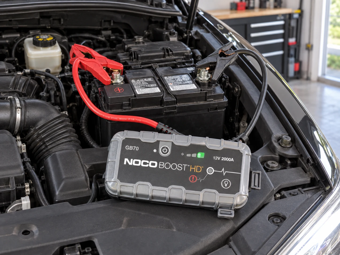 NOCO Boost GB70 connected to a vehicle battery in a home garage